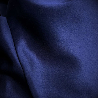 Close-up van de gladde, glanzende stof van een blauwe satijnen kussensloop van moerbeizijde.